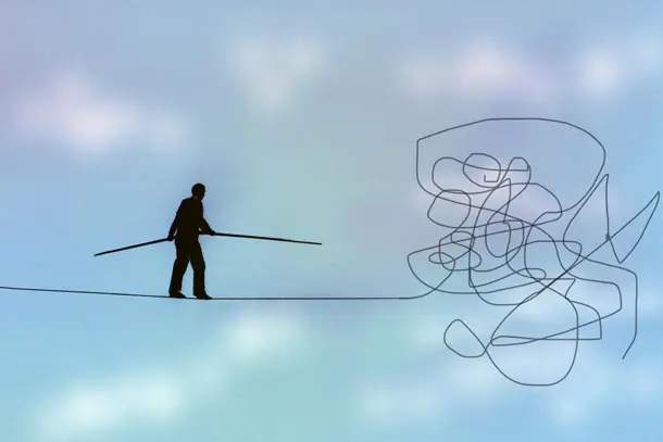 Silhouette of a person walking a tightrope toward a tangle of lines, symbolising the balance and pressure people feel when dealing with stress