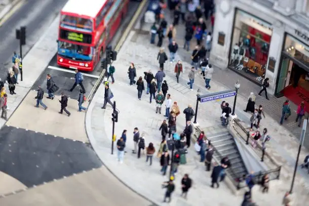 Busy street scene outside Oxford Circus Station in London, with people crossing the road and a red double-decker bus passing. Capturing the energy of the city where Face2Face counselling services are based