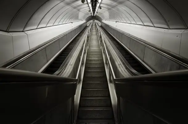 Empty escalator in a London Underground station, leading upward through a curved tunnel, symbolising a journey or personal progress, reflecting Face2Face’s location in London